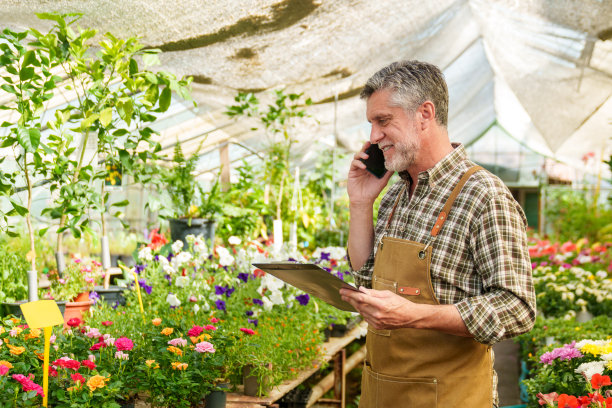 花圃工人接受客户订单:手拿手机，拖着文件夹图片下载