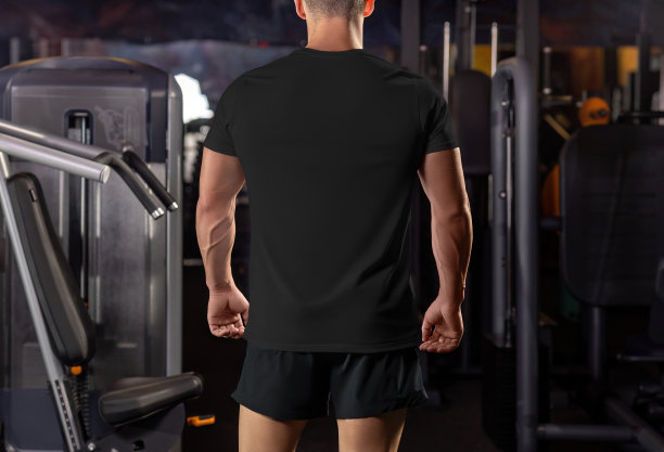 一个肌肉男穿着黑色t恤的模型，背景是健身房的器材，后视图。图片下载