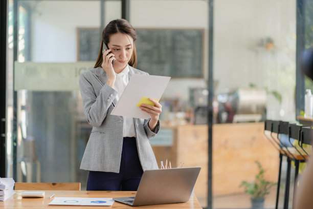 有魅力的千禧一代亚洲女商人和一个拿着文件的人打电话站在经理办公室拿着文件阅读财务文件的职业女性图片下载