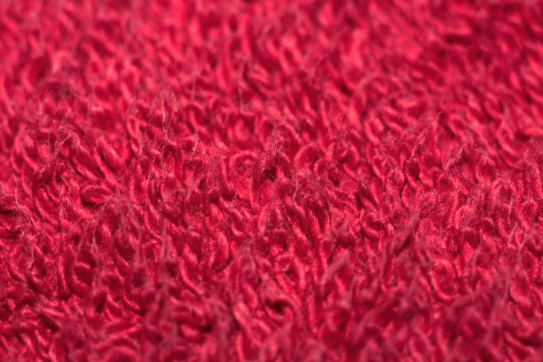 一张红色羊毛地毯的特写作为背景。宏红毛织品的质感。图片下载