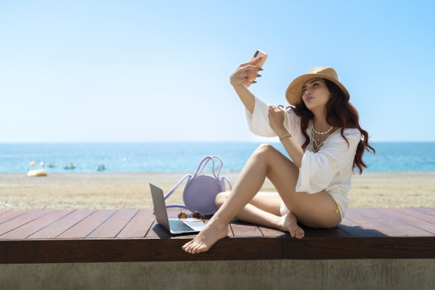 女孩在沙滩上使用手机。图片下载