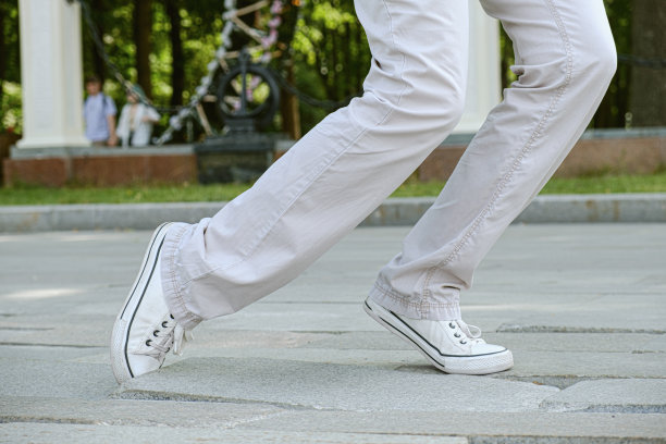 穿着浅色裤子和运动鞋的妇女在凹凸不平的路面上跌跌撞撞图片下载