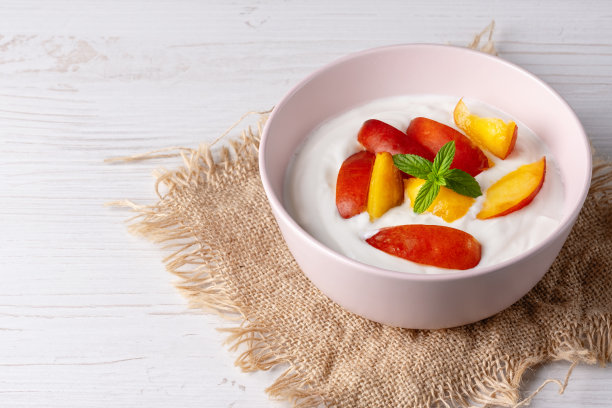 粉色碗装新鲜白干酪，白色底配薄荷叶和桃片图片下载