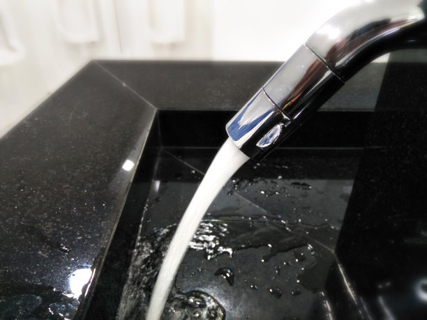 卫生间和豪华的现代风格，封闭的开放式金属水龙头水流降至盆为黑色大理石、黑色陶瓷水槽图片下载