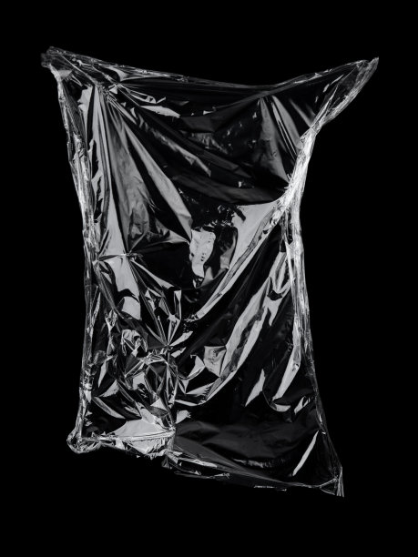 透明的保鲜膜纹理在黑色背景上。塑料袋质感。可重复使用的垃圾和废物。图片下载