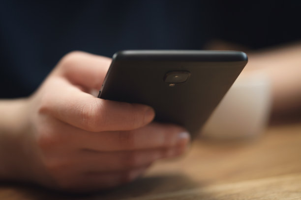 年轻的女青少年手握智能手机坐在桌子旁的特写图片下载