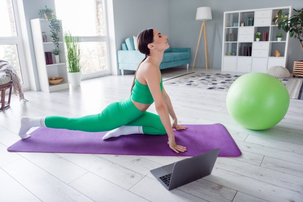 漂亮可爱的女孩穿着运动服在家里练习网络瑜伽课设备的照片图片下载