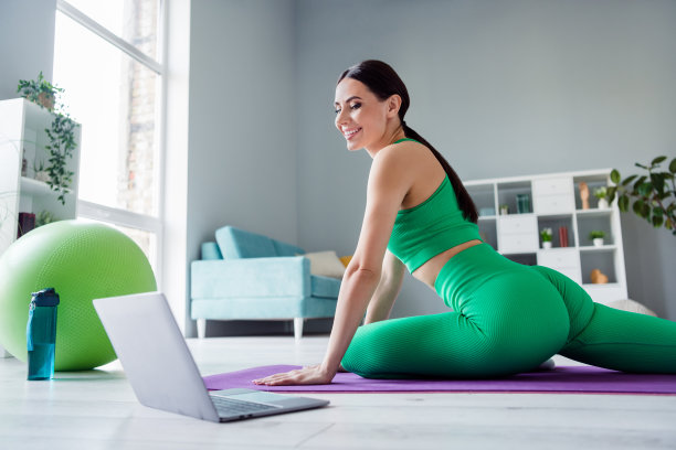 个人资料照片有吸引力的运动的人伸展腿健身地毯看视频上网本早上的房子在室内图片下载