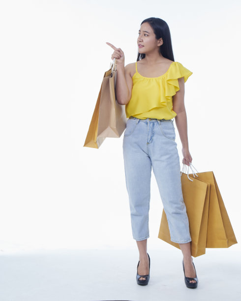 漂亮的年轻女子拿着白色背景的购物袋图片下载