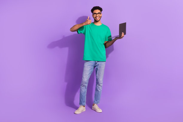 帅哥拿着上网本的全身照片，在紫色背景上展示大拇指向上图片下载