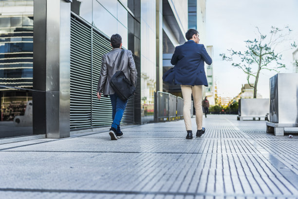 两个同事走在街上去开会的后视图图片下载