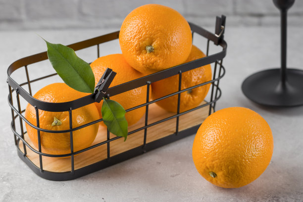明亮的桌子上，金属篮子里装着新鲜橙子。早餐健康食品理念。有机产品。含新鲜柑橘类水果，图片下载