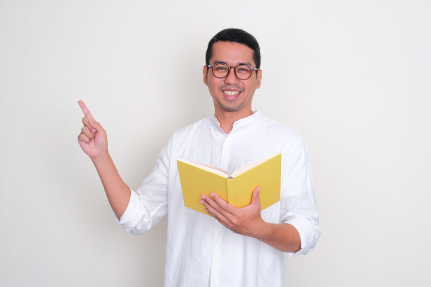 亚洲成年男子拿着一本书，微笑着指着右边图片下载