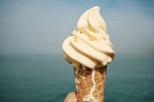 六月晴朗的一天，康沃尔郡纽基，美味的融化香草甜筒俯瞰着散焦的大海。图片下载