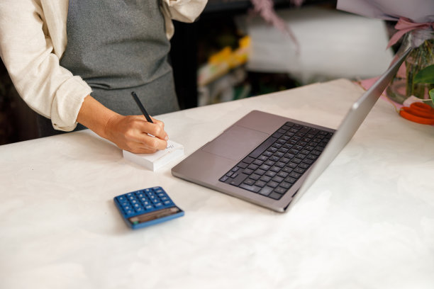 花店老板花店老板使用笔记本电脑和在笔记本上写在花店的特写图片下载