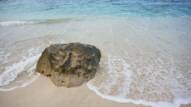 沙滩上的珊瑚或岩石被带泡沫的蓝色海水拍打着。欣赏美丽的热带海滩，岩石，珊瑚，海浪，沙滩和南榜卡连达的滨海海滩图片下载