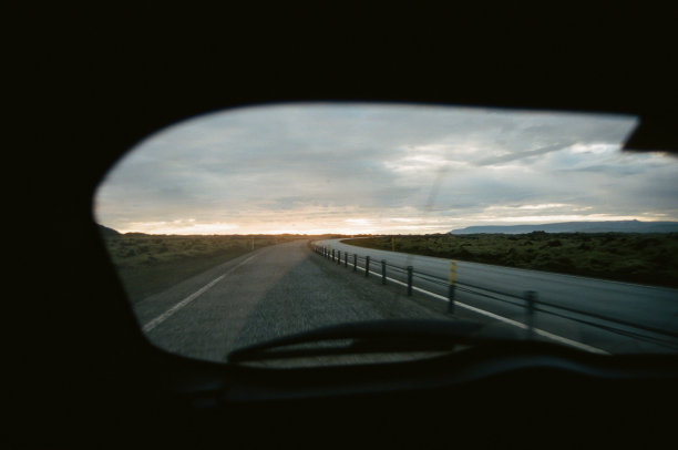 在冰岛的高速公路上，夕阳照进了汽车的后窗。胶片摄影图片下载