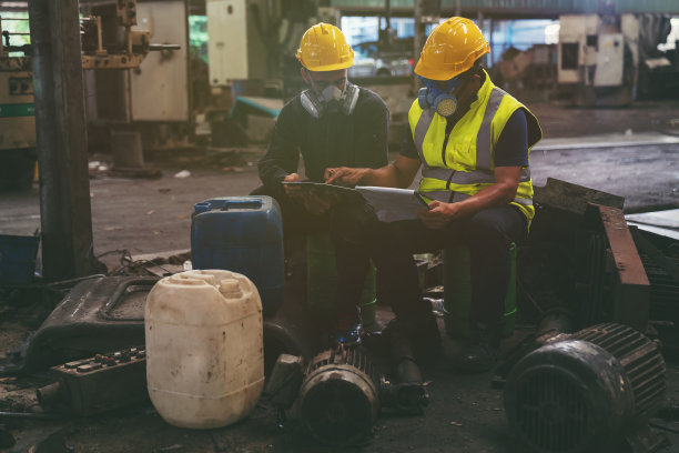 化学品泄漏和安全第一的理念。化工专家小组在工业工厂穿着安全制服，戴着防毒面具检查化学品泄漏。两位科学家正在检查植物中液体的质量图片下载