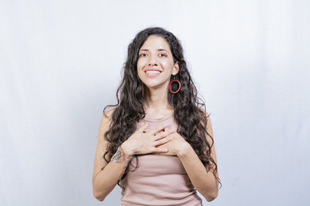 积极的女人带着可爱真诚的微笑感到感激，放松的人用手放在胸前表示感谢，感恩的人的概念图片下载