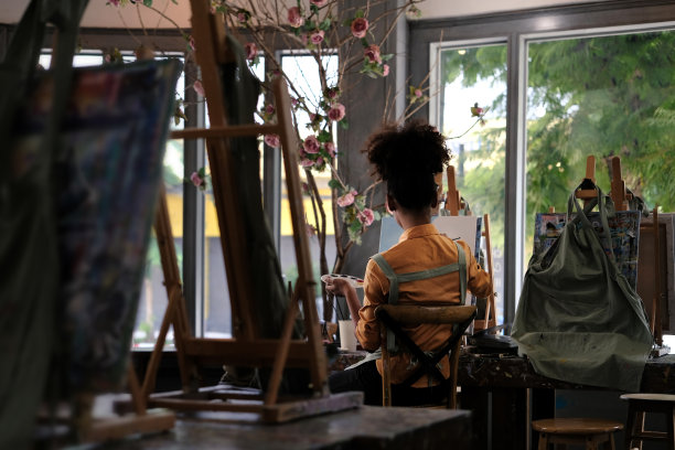 背后的灵感年轻卷曲的女学生在画布上画画，独自坐在艺术工作室。图片下载