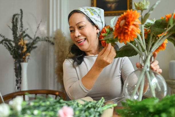 快乐的中年妇女在花店用鲜花制作花束。退休，花艺和小企业的经营理念。图片下载