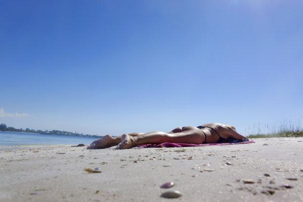 穿着比基尼的单身女子在白色的热带沙滩上晒日光浴图片下载