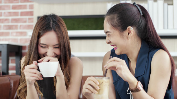 两个年轻的亚洲女性朋友在度假时喜欢在咖啡馆聊天。快乐的年轻女子与欢乐聊天，开怀大笑，放松和微笑。女性生活方式理念图片下载