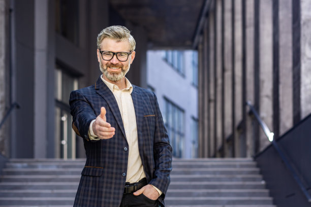 成熟成功的花白头发商人微笑着看着镜头，手牵手在前握手打招呼，经验丰富的老板图片下载