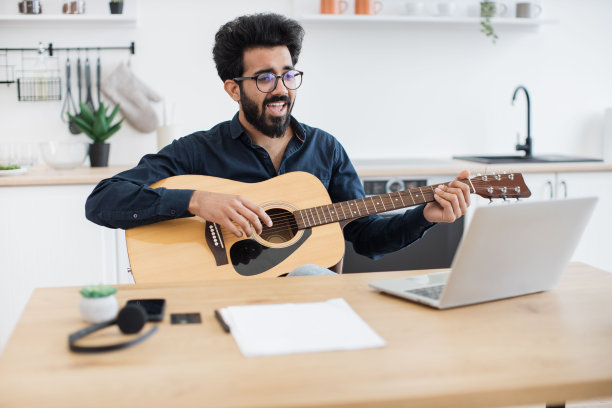 音乐家在家用吉他和电脑作曲图片下载