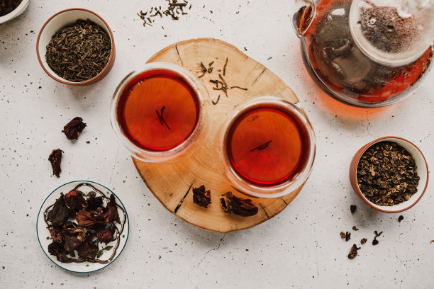 不同种类的茶。黑色、绿色和木槿色在一张白色的桌子上摆放着茶壶和玻璃杯。图片下载