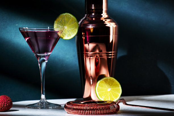 马提尼杯，含伏特加、干金酒、荔枝、酸橙和冰的酒精鸡尾酒，深绿色背景，明亮的光影图案图片下载