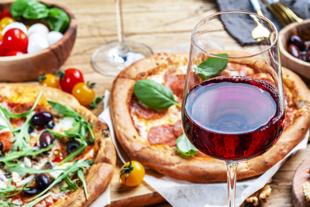 披萨派对的餐桌。红酒酒杯和盘子，质朴的木桌，热披萨，意大利开胃菜，沙拉，奶酪，水果和浆果。家庭午餐和快餐图片下载