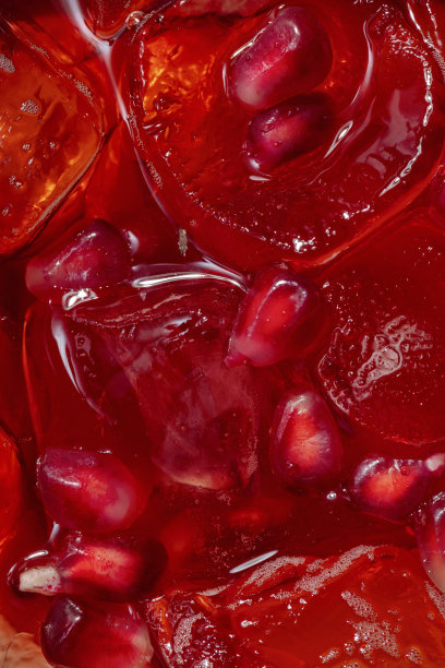 石榴的喷流。高脚杯鸡尾酒，加冰块和石榴。旁边是一整块石榴。玻璃杯立在一块薄桌布上。图片下载