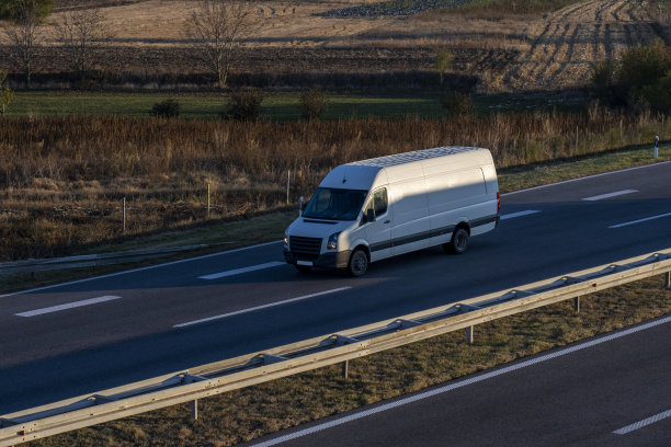 高速公路上的白色货车。白色现代快递小件货物快递车在高速公路上快速行驶到城市郊区。世界上最好的货物运输。图片下载