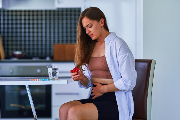 不健康的痛苦的年轻女子遭受胃痛和抱着水泡包止痛药药。健康问题图片下载