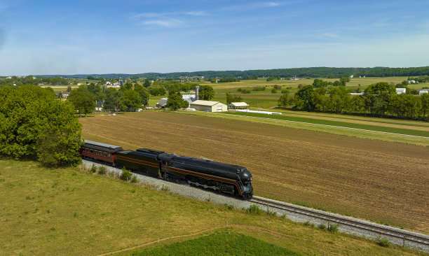 现代蒸汽机车拉着客车穿过农田的鸟瞰图图片下载