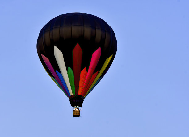 黑色带彩色条纹的热气球在蓝天中飞翔图片下载