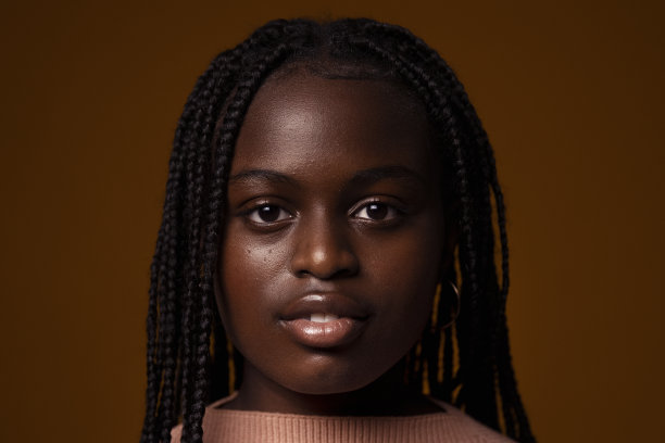 一个严肃的少年在深棕色背景下的肖像图片下载