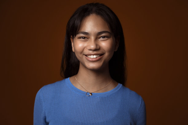 一个快乐的少年在深棕色背景下的肖像图片下载