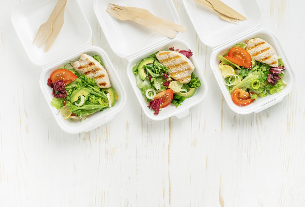 白色木制背景的午餐盒里有沙拉和烤鸡。俯视图图片下载