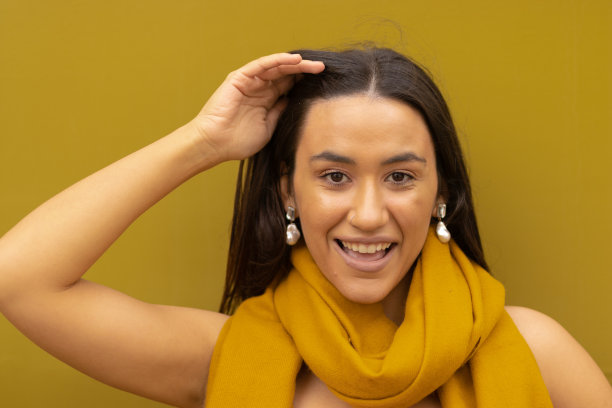 年轻的美国土著妇女对着镜头微笑，背景和服装的色调相匹配。图片下载