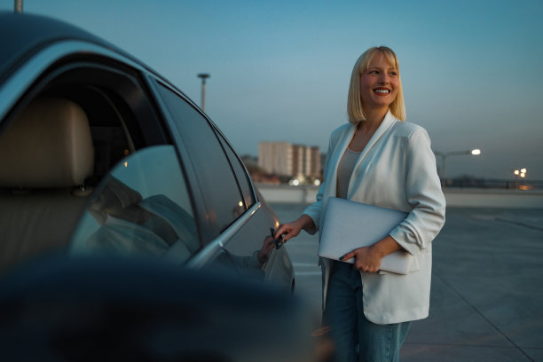 女性领导人。年轻漂亮的女商人穿着时髦的西装拿着笔记本电脑上了一辆黑色的车。经营理念图片下载