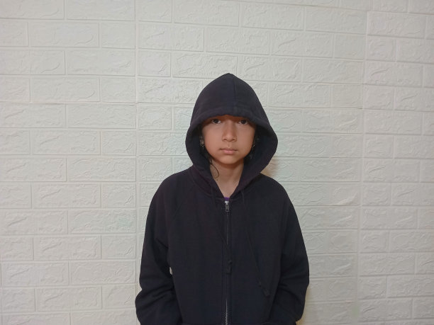 一个十几岁的女孩穿着连帽衫，在摄影棚里对着镜头摆姿势。
人看着镜头。图片下载