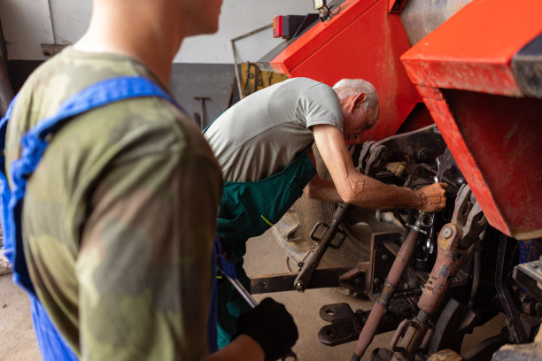 父亲和十几岁的儿子正在修理拖拉机图片下载