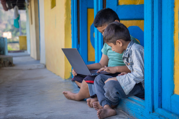 村里的孩子坐在门口玩笔记本电脑图片下载