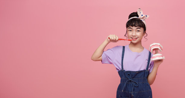 亚洲可爱的小女孩微笑着拿着牙颌和牙刷。儿童口腔卫生训练。孩子学习刷牙、清洁牙齿。预防儿童龋齿。图片下载