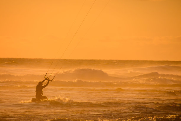 日落时在平静的海面上冲浪者图片下载
