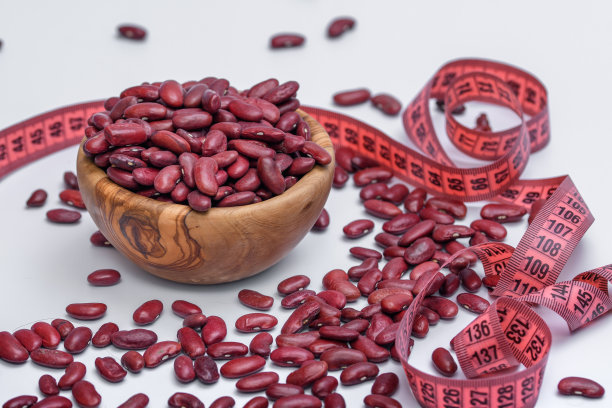 膳食红豆，散落在一个木碗周围，周围是卷尺，卷尺图片下载