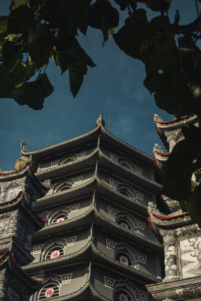 越南岘港灵应寺舍利塔，蓝天白云背景，绿叶前景，侧视图图片下载