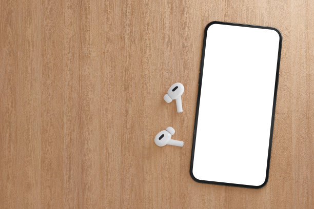 现代智能手机，屏幕空白，木桌上有无线耳机。木制背景上的TWS耳机与智能手机的模型。本空间图片下载